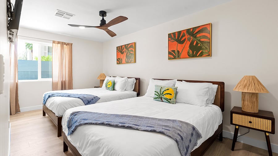 Tropical-themed bedroom with queen beds, palm throw pillows, and island decor art