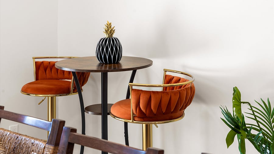 Velvet orange bar stools and gold rimmed table with wood pineapple centerpiece