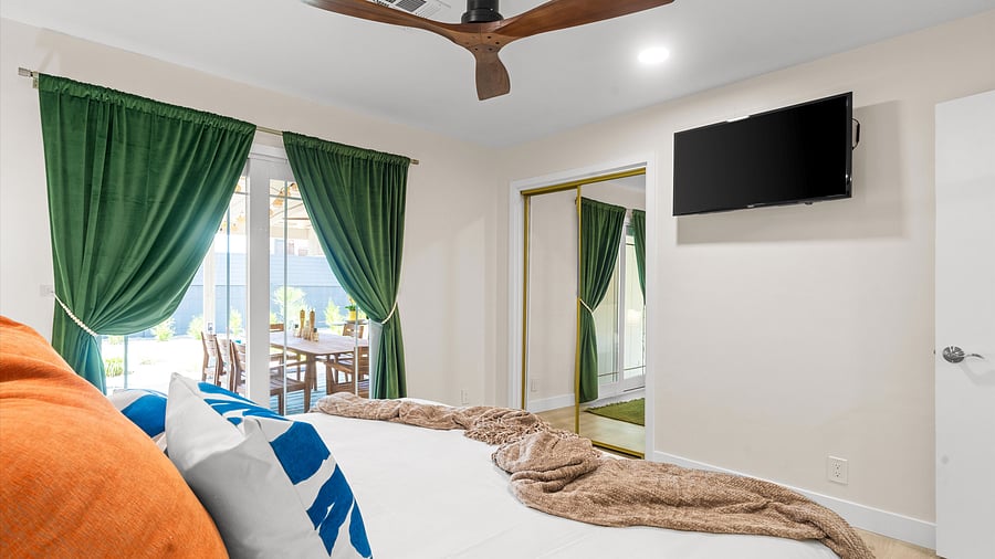 Smart Tv for relaxing in your king bed looking out to the patio dining area through elegant emerald curtains