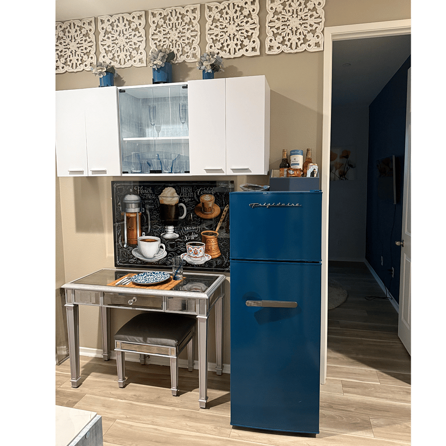 Kitchen cabinets with dishes, glasses, wine glasses, seating, and refrigerator