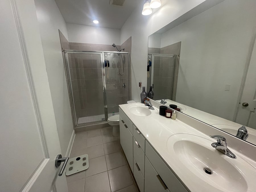 Clean, minimalist bathroom with double sinks, full shower, and modern finishes.