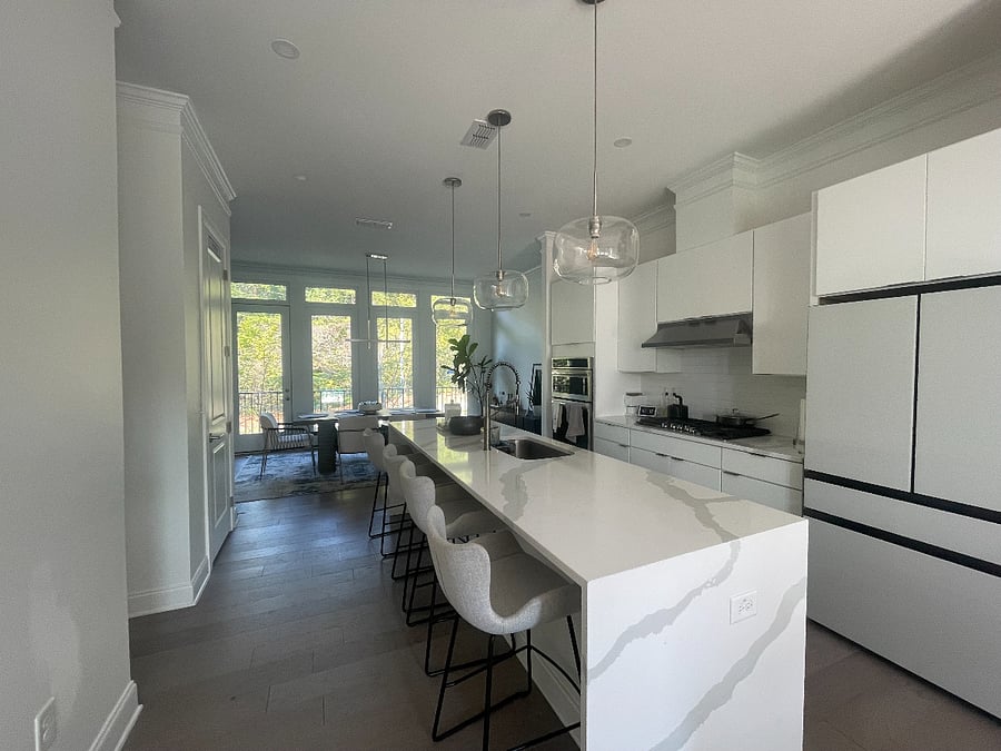 Cook and gather in a luxury kitchen with waterfall island, 5-burner gas stove, smart fridge, microwave/oven, dishwasher, and wine fridge.