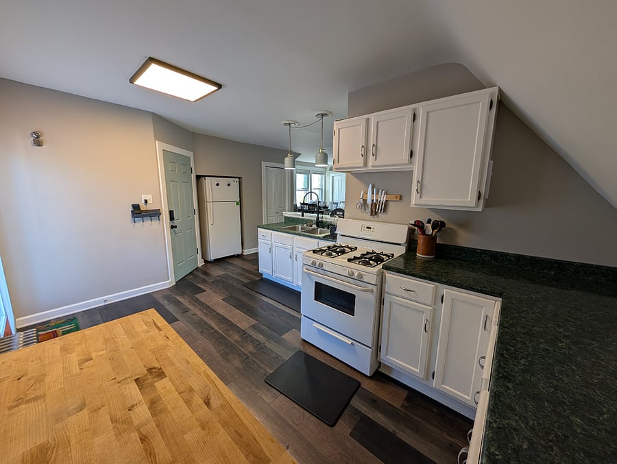 Kitchen with gas oven, microwave, air fryer, coffee pot, coffee grinder, pots, pans, tupperware, silverware, garbage disposal, butcher block movable island.