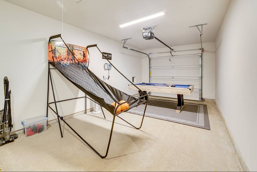 Game room in garage with pool table and arcade game. Tower Fan