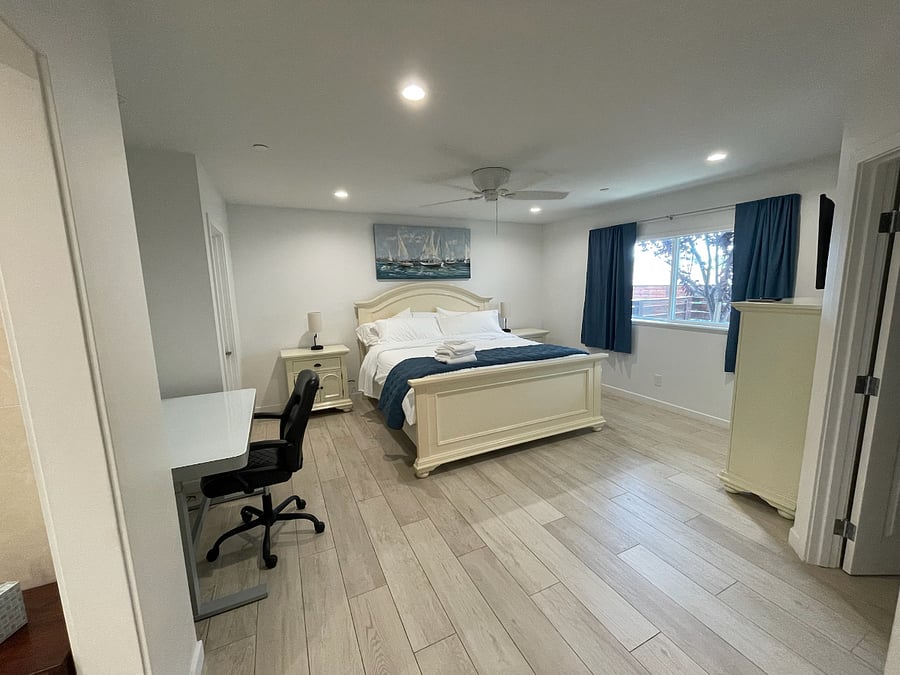 Primary bedroom, with en suite bathroom, King-size bed, adjustable height desk in workspace, walk in closet, room darkening curtains, dresser and nightstands