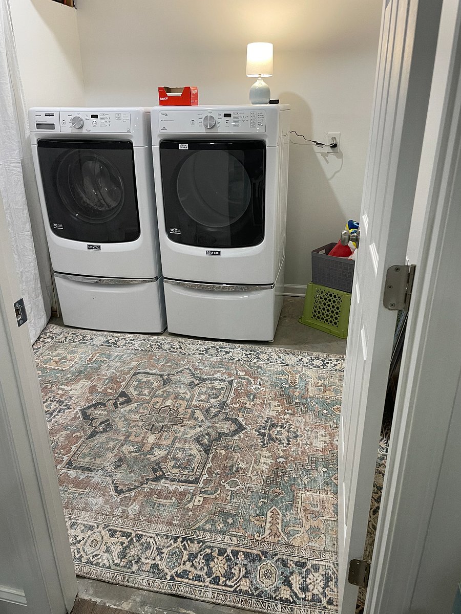 Utility laundry room with cleaning supplies, under machines storage and a console table for extra storage and folding surface.