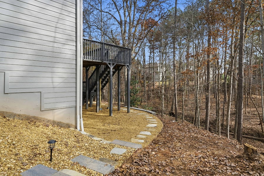 Professionally landscaped/hardscaped walk path with lights to the private entrance just beyond the fence with a fully fenced back yard. Featuring a solo stove and seating area. 