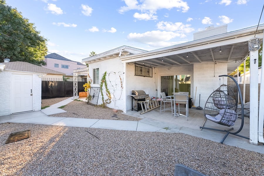 Covered back patio in the backyard that has seating and bbq grill.