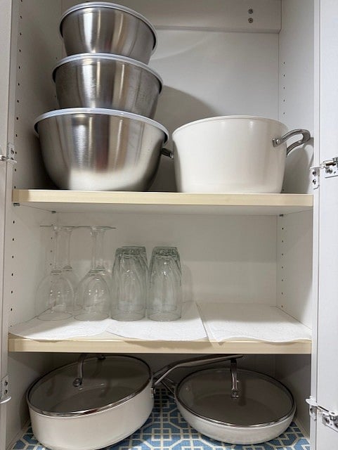 Additional pot, pans, colanders, serving plates are stored under the counter
