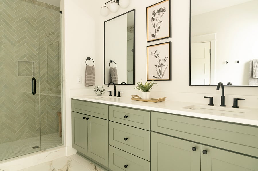 Bathroom for main bedroom with double sink, glass door shower, and separate toilet room