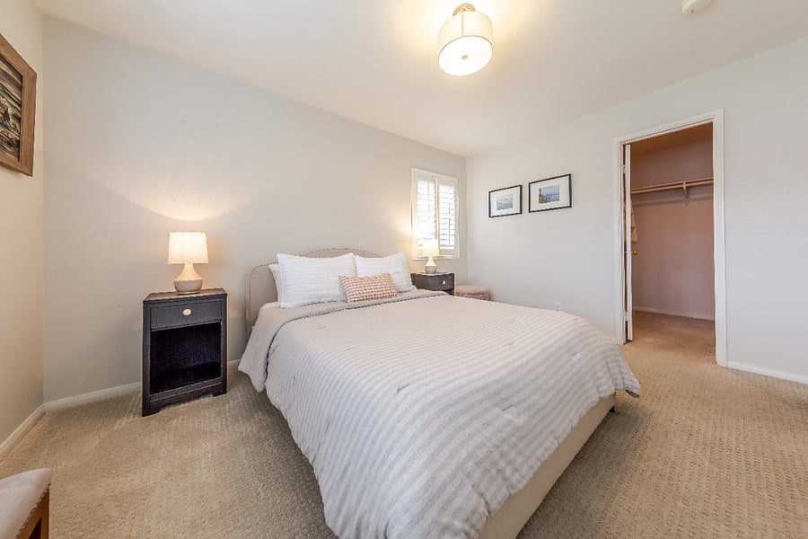 Bedroom with queen bed, all bedding, end tables, lamps, ottoman and bench.