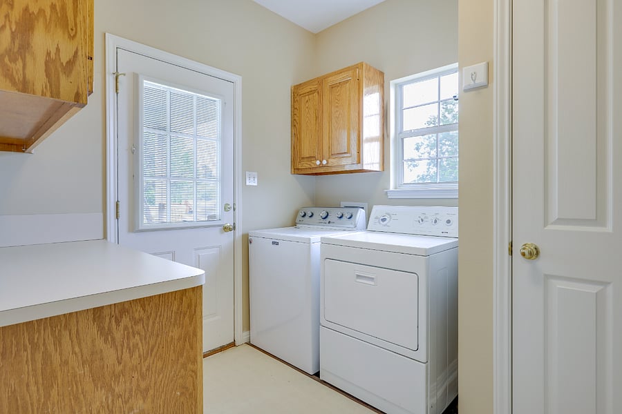 Large laundry room with closet and shelf storage and access to back porch with gas grill