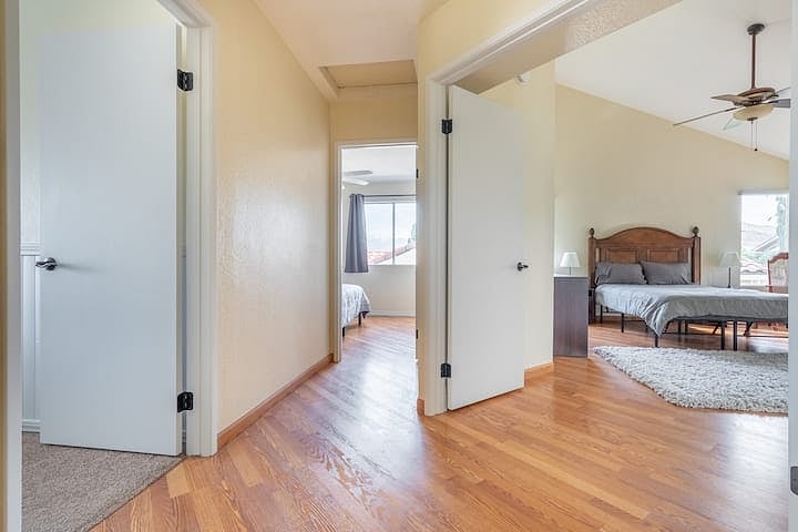 Once at top of the stairs, you can enter both the two bedrooms (center and left) or the primary bedroom suite (right, through double-doors).
