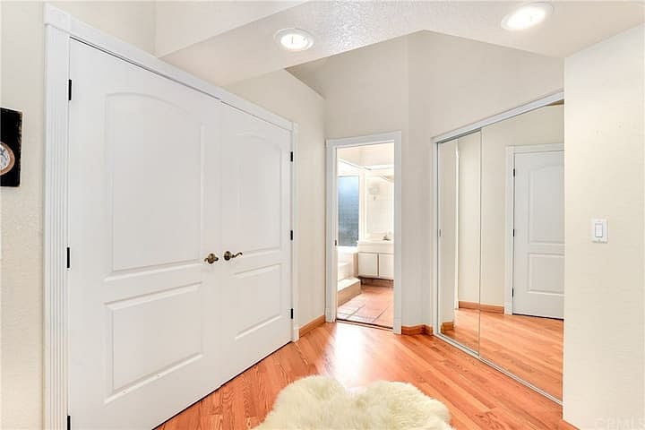 Primary suite has double-door access to a very spacious walk-in closet (on left) and double-wide sliding glass closet (on right). Primary suite bathroom entrance in center of photo.