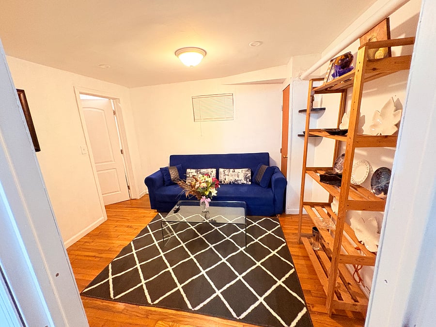 Comfortable and inviting living room featuring beautiful hardwood flooring, a cozy sofa, and a stylish area rug that creates a warm and welcoming atmosphere. The space offers a practical layout with plenty of room for relaxing, entertaining.