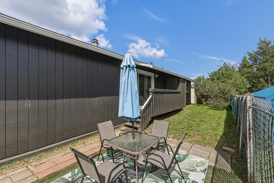 Exterior back yard with small, covered porch and outdoor seating area. Fully fenced