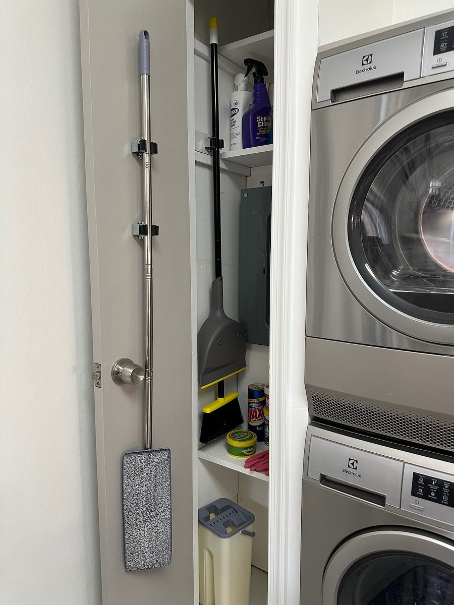 Closet with a light mop, broom and dustpan, allow with cleaning supplies.
