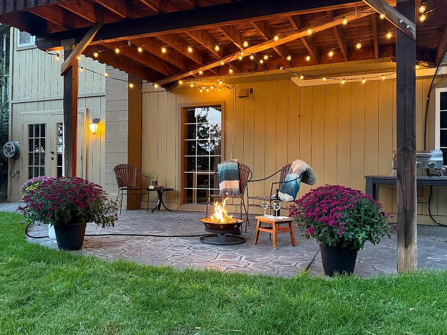 Spacious patio with cafe lights, seating, barbecue, and propane fire pit for year-round evening gatherings.