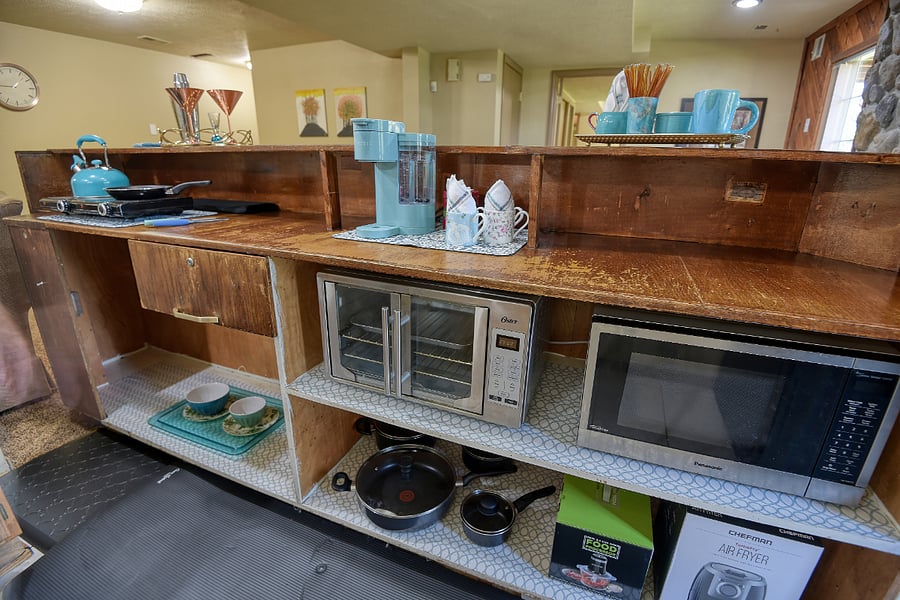 Vintage bar converted to a fully equipped kitchen with themed Keurig and coffee station, stove top, toaster oven, microwave, air fryer, teapot, and food processor, accented with turquoise touches for a stylish, functional space. The refrigerator is clean with a full freezer; it is a little dated, and drawers/door racks have been reduced. Please note: there is no standard oven. All cupboards are stocked with themed cookware, dishes, and utensils for your convenience (including a pizza cutter and can opener).