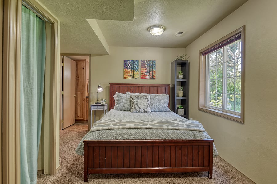 Queen bed with 400-thread-count Egyptian cotton sheets and a variety of plush pillows offers luxurious comfort, with sunlight and lush yard views through large windows equipped with blinds for restful sleep.