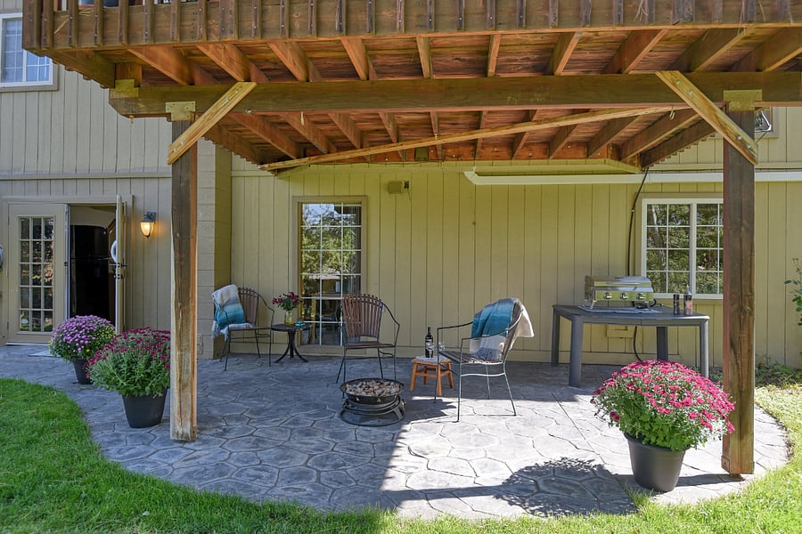 Extra-large covered porch with barbecue, grilling area, and cozy reading nook, offering a serene space to enjoy meals, relax, or watch the sunlight filter through the yard.