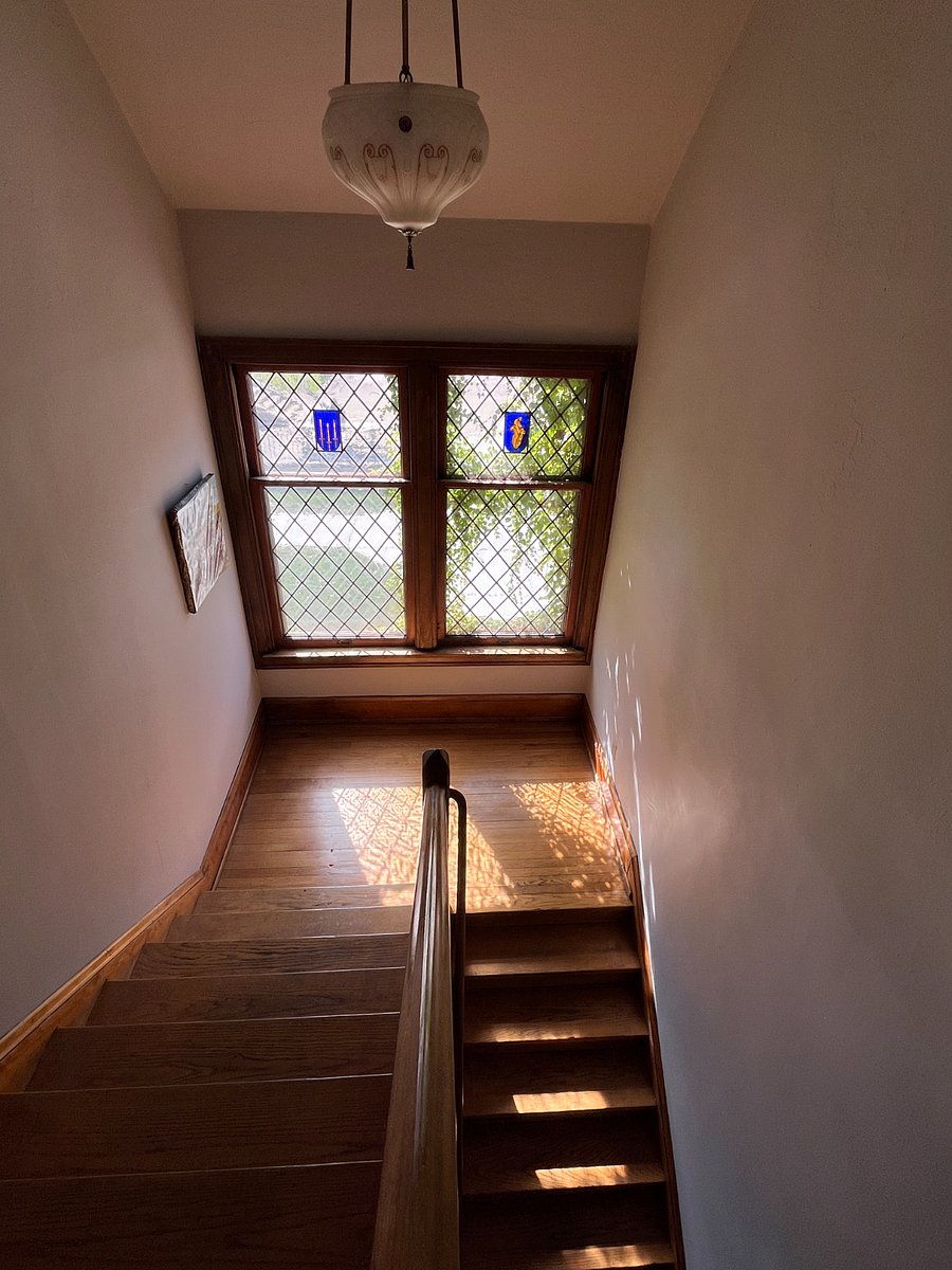 Grand staircase with stained glass and leaded glass windows overlooking a church courtyard