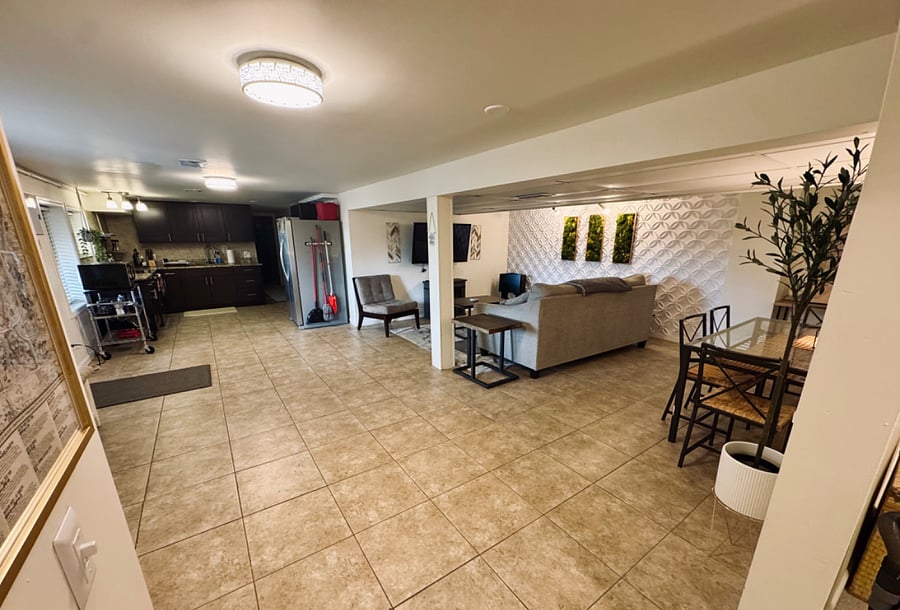 Basement apartment view including living room, entrance, dining table and kitchen areas.