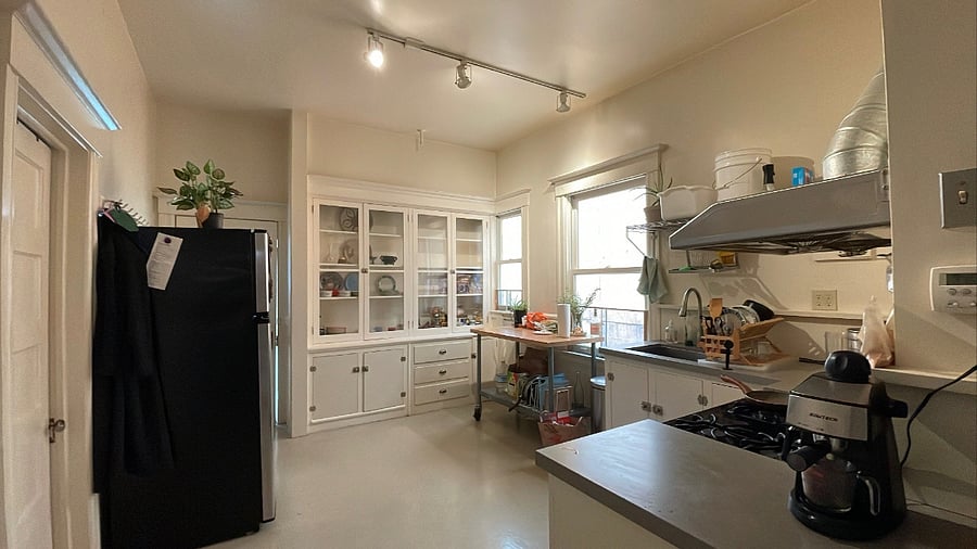 Kitchen angle from the living room, featuring the stove, oven, pantry, full fridge, espresso maker, and mobile island.