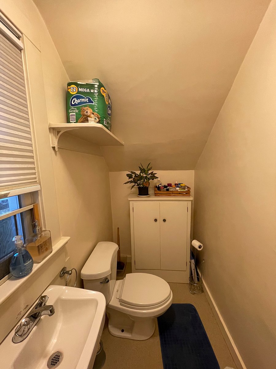 Restroom with toilet and sink, as well as additional storage space.