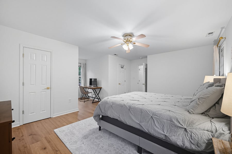 Large secondary bedroom with queen bed, ceiling fan, desk, dresser, and nightstands. Comfortable and quiet for extended stays.