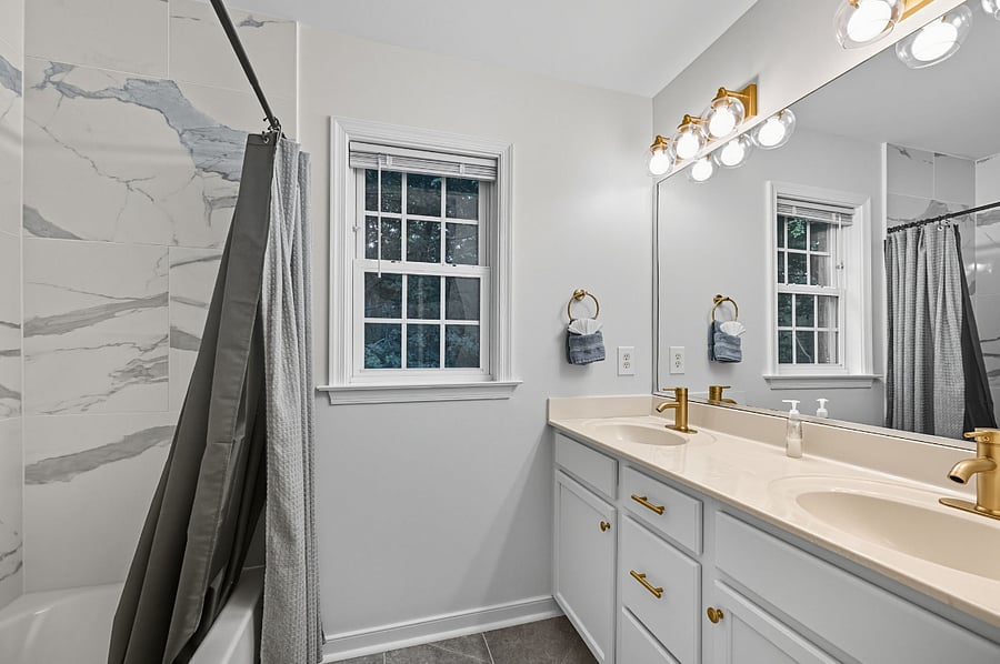 Updated bathroom with double vanity and modern shower/tub combo  clean and functional.