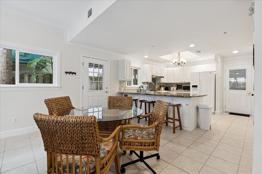 Bright dining area with woven chairs and open kitchen for easy gatherings.
