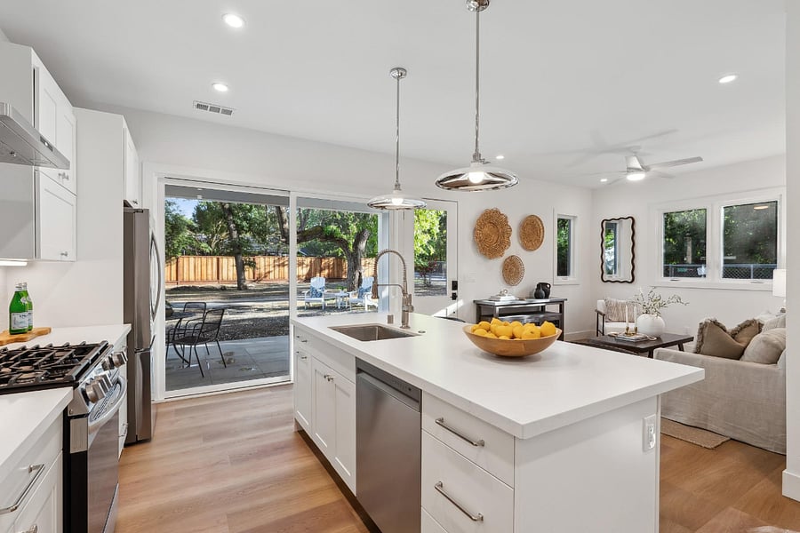 Kitchen and living area with large island that seats 4+. A modern fence now encloses the house for privacy and an area for a dog. 