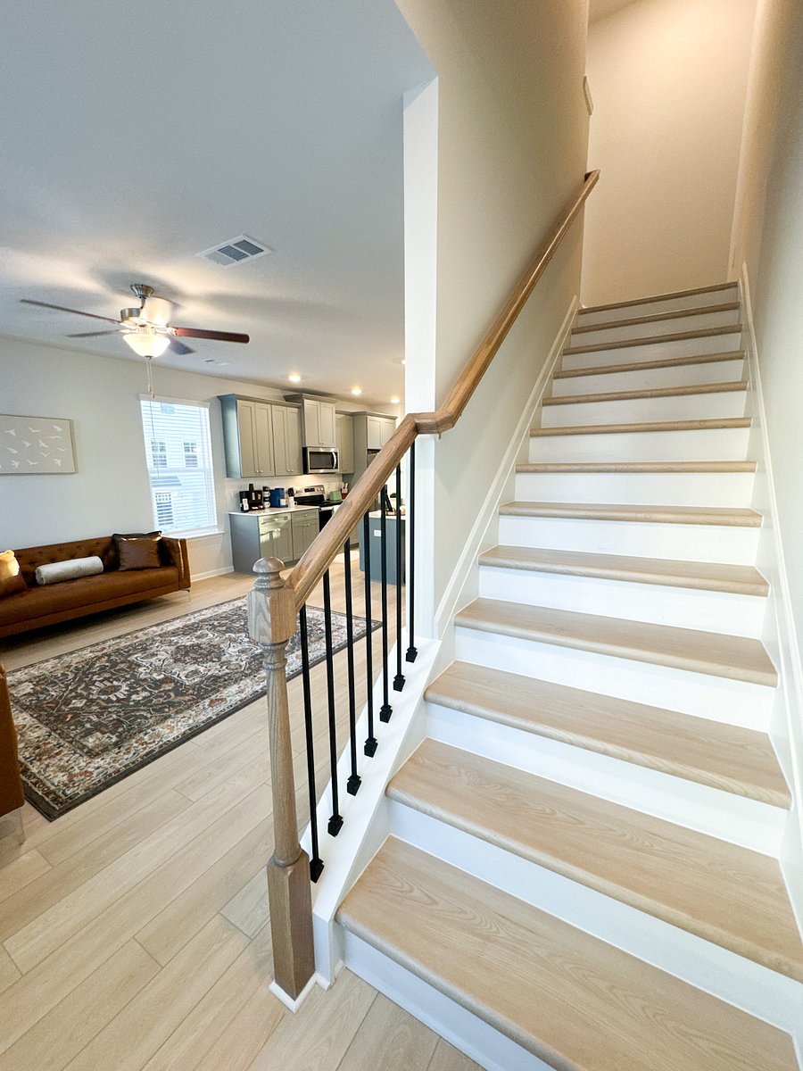 The living room seamlessly connects to the upper floor via a well-lit staircase, leading to cozy and private bedrooms for a restful nights sleep.
