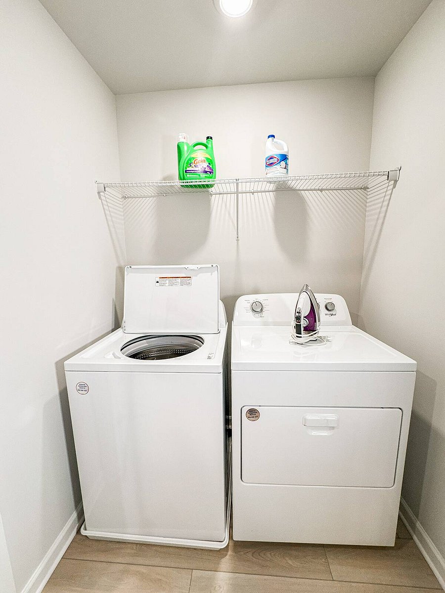 Laundry area with washer, dryer, detergent pods, and an iron for your convenience
