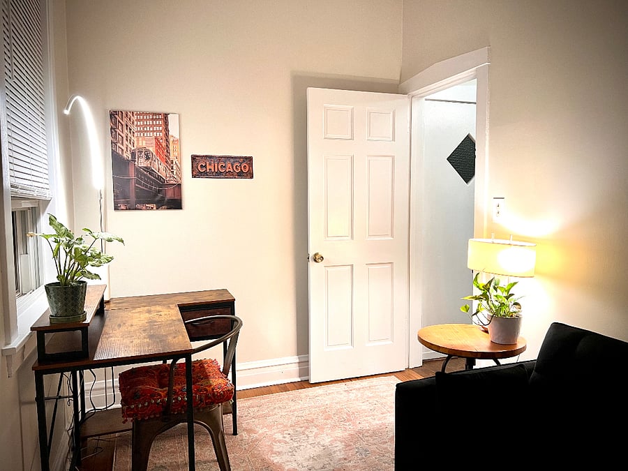 The Chicago Room - second bedroom - this is a view from the closet of the Chicago Room and shows the warm lighting, cozy environment, and desk for anyone working from home, digital nomads, or other working professionals in need of dedicated workspace. If you need more room to spread out, you can also use the 6 ft long glass table in the dining area as it also functions as a wonderful desk and work area.