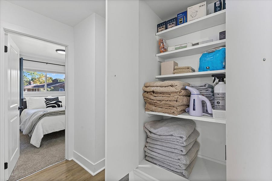 Extra towels and supplies in linen closet including wrinkle spray, steamer,