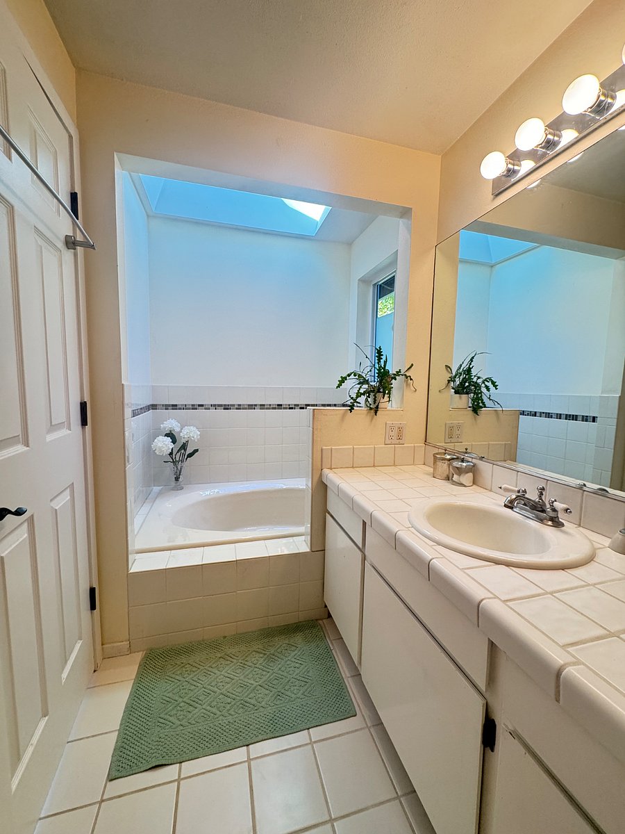 Bright master bathroom with large soaking tub, skylight above, and separate shower.