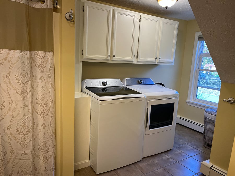 New washer and dryer with hamper in spacious bathroom.