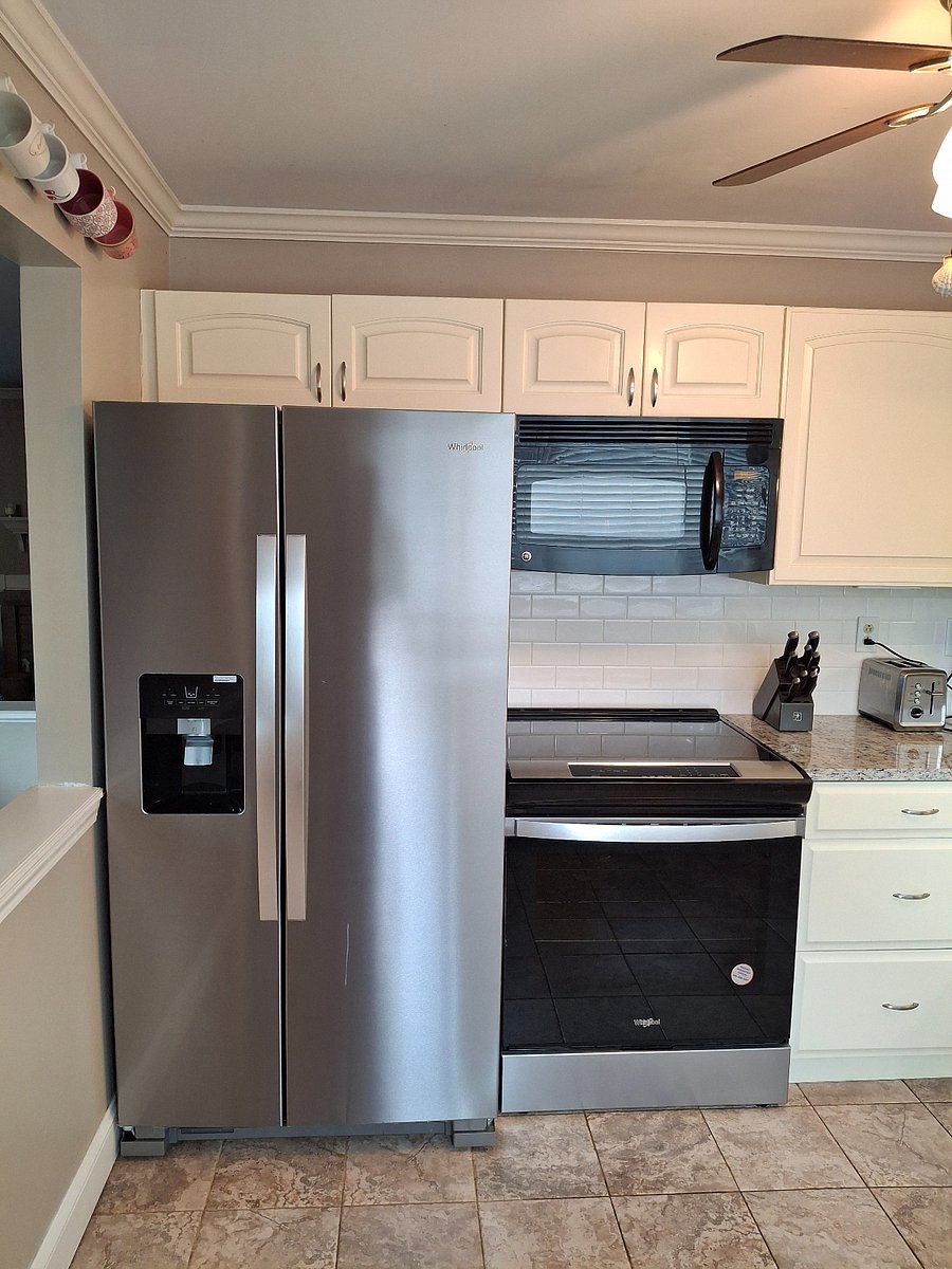 Kitchen area, with microwave and electric stove, and stainless steel fridge. 
