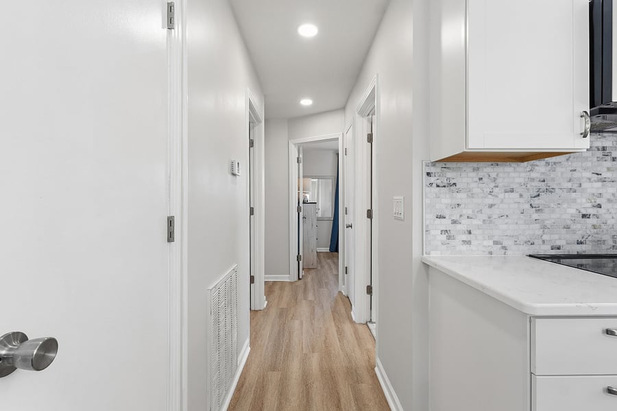 Hallway has 2 closets. 1 with cleaning supplies, 1 as coat closet.