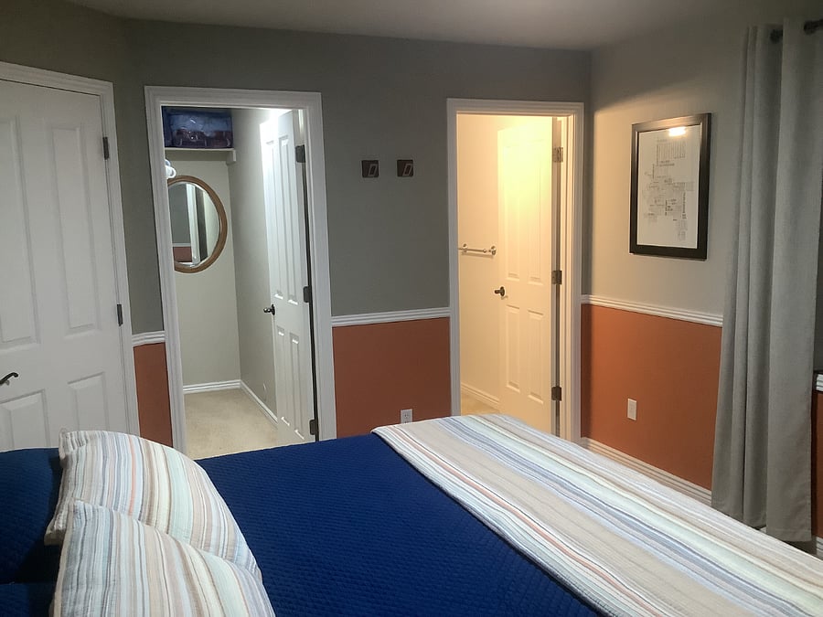 East wall with walk-in closet, bathroom, and entry doors.