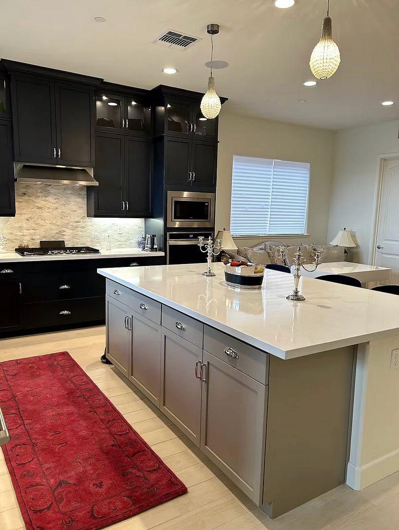 Kitchen with huge center island, marble backsplash, farmhouse sink and stainless steel appliances.