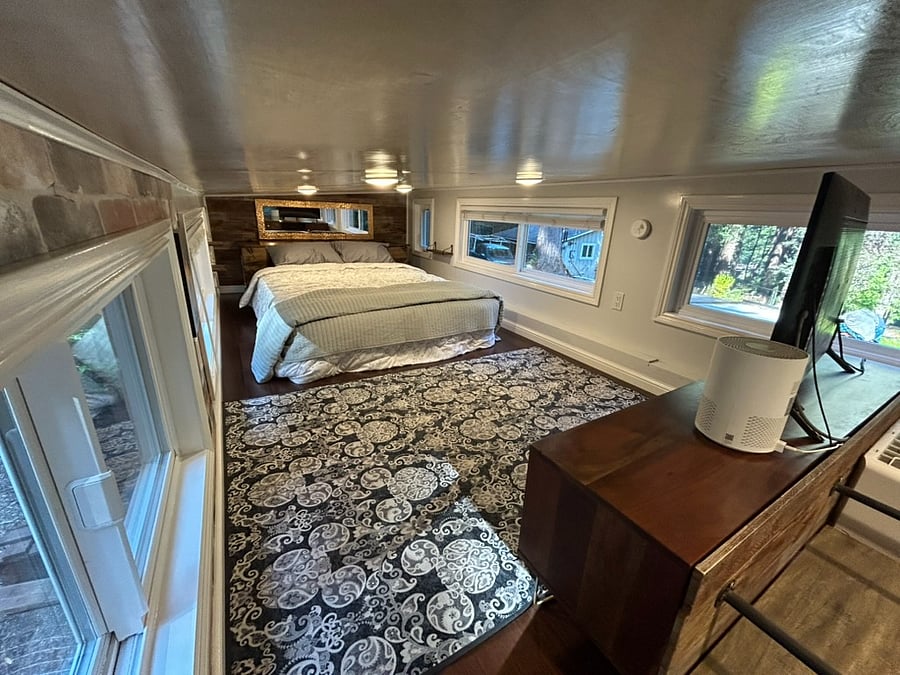 Main lofted bedroom has a queen bed, blackout curtains on all six windows, a smart TV, more storage and air purifyer.