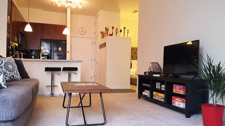 Open-concept floor plan - bedroom separated from kitchen and living area by a partial wall lined with tap handles.