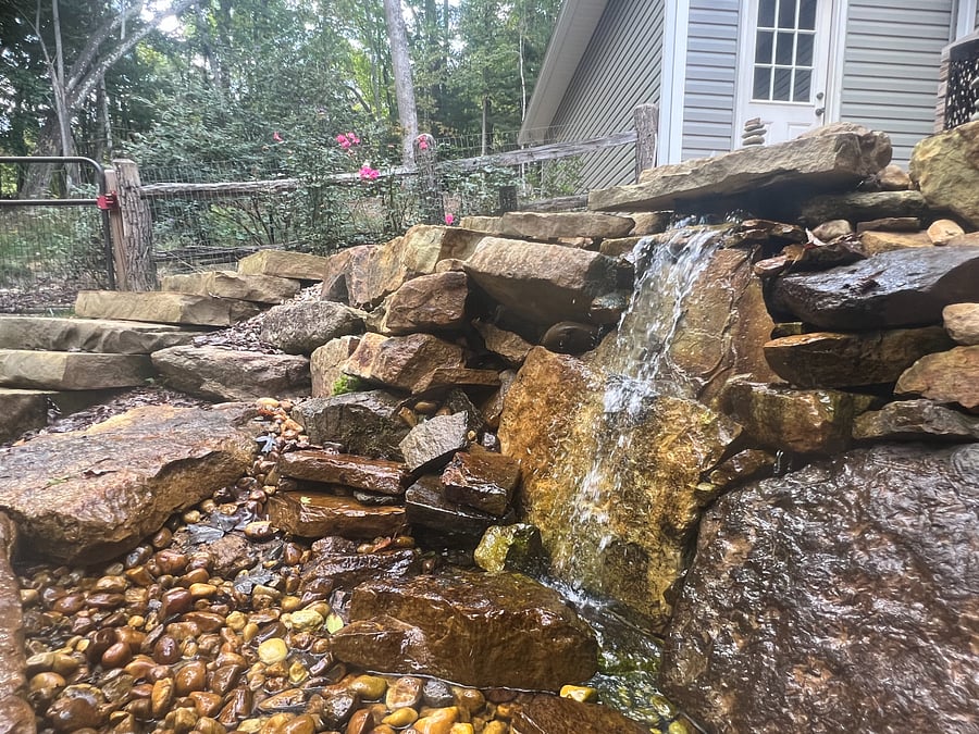 4 foot mini waterfall in backyard off of the screened porch