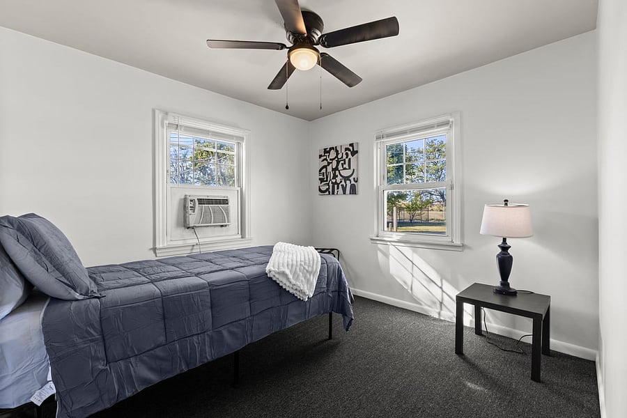 Bright and cozy second bedroom with a twin bed, reading chair, and soft linens perfect for solo travelers, kids, or guests needing extra space.