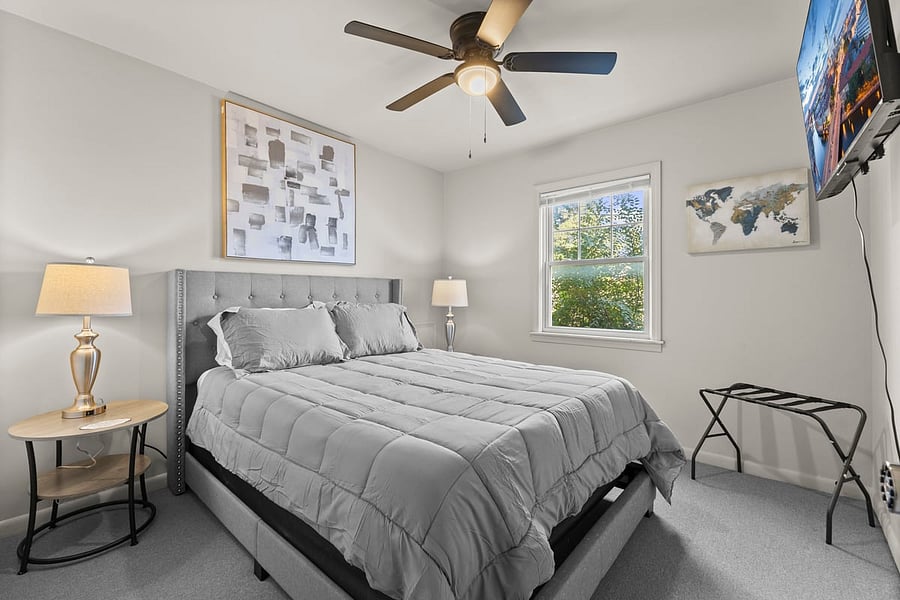 Peaceful primary bedroom with soft gray tones, queen bed, and 50 Smart TV ideal for restful nights. Both lamps have USB Cords for all your charging needs.