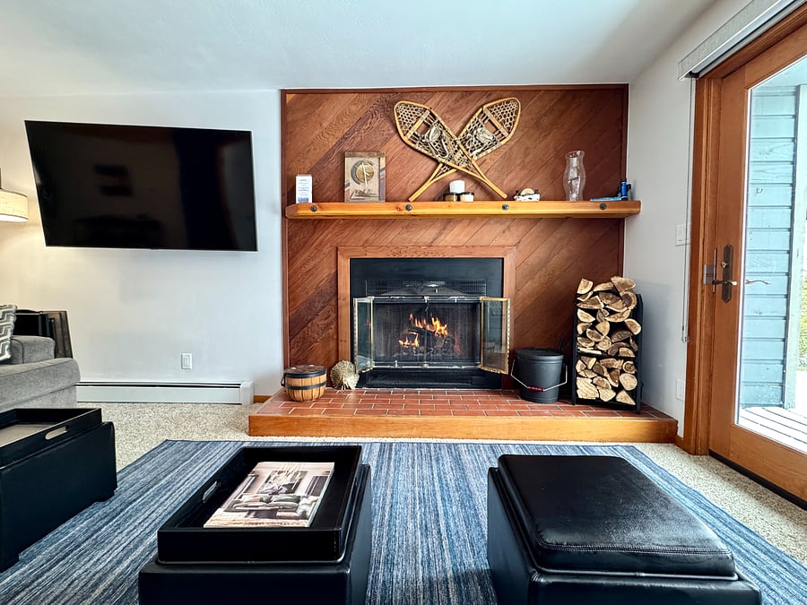 Living room w/ wood burning fire place, and smart TV.