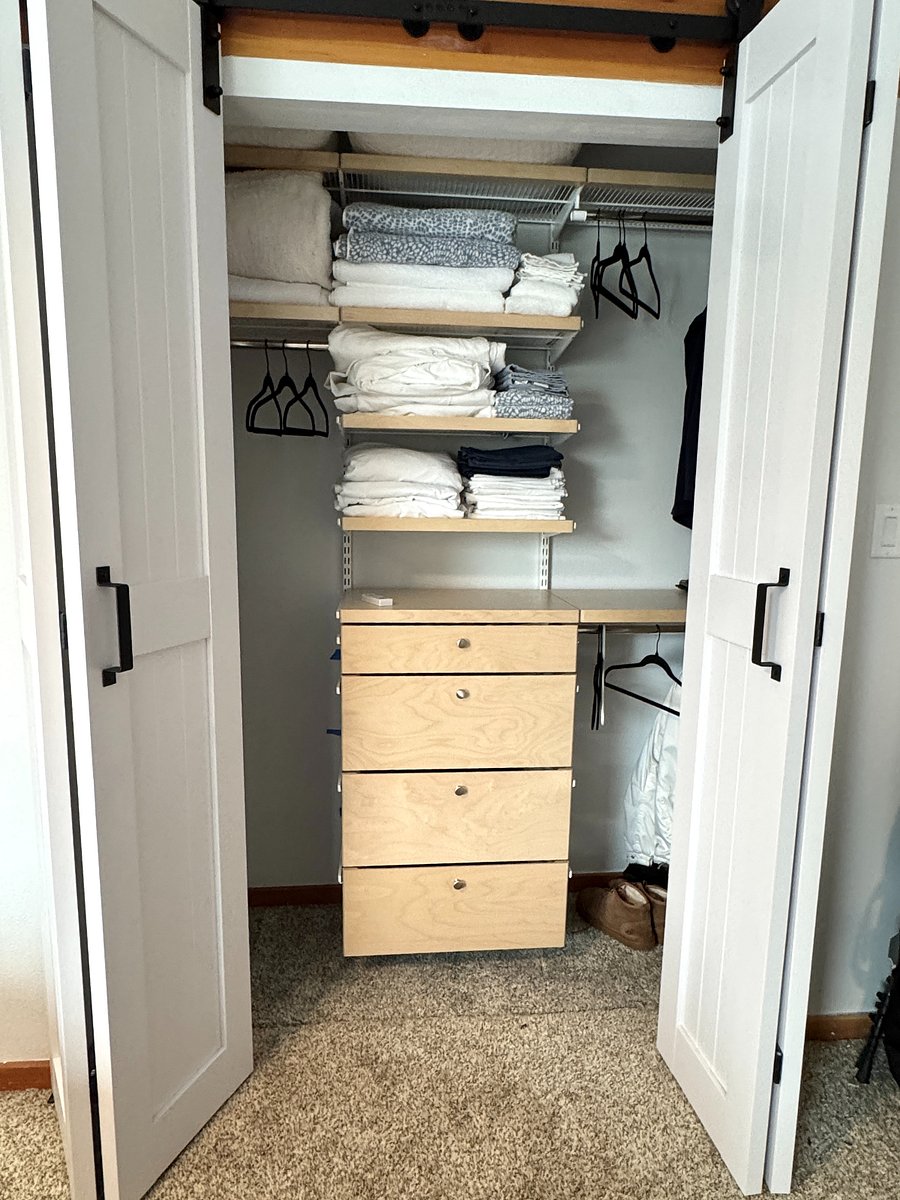 Bedroom closet has closet system with multiple hanging areas and drawers.